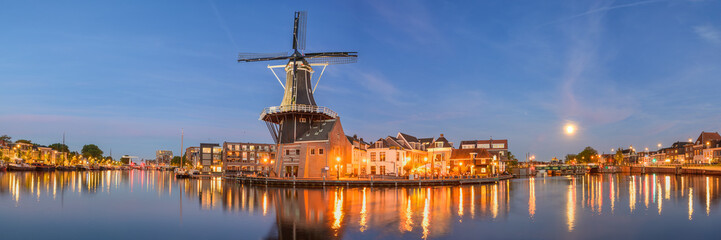 Windmill de adriaan and cityscape reflections on spaarne river in haarlem, netherlands