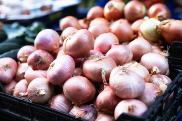Box is filled with onions, grocery store display case.