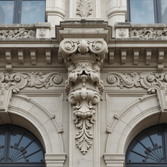 The Italianate stucco facade, with its curved scrolls, acanthus leaves, and festoon details along the cornices, is enhanced by textured reliefs that create a rich, Old World opulence