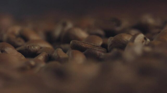 Roasted coffee beans are piled up, creating a textured landscape of rich brown hues, inviting viewers to appreciate the aromatic essence of a beloved beverage