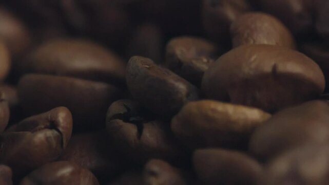 Roasted coffee beans densely packed and filling entire frame, revealing rich brown texture with deep organic layers representing coffee's natural aromatic complexity