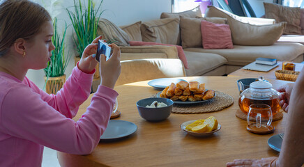 Relaxed tea moment with teapot and smartphone on wooden table. Bright natural light and cozy atmosphere in modern living room