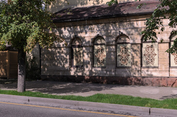 view of the wall of the building with arched windows decorated with ornaments with shadows from a tree