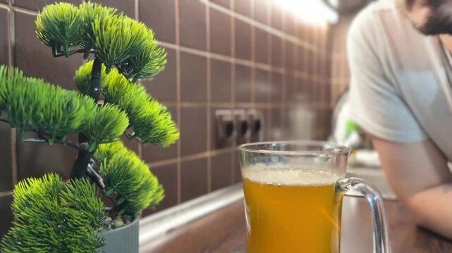 A man sniffs a kombucha SCOBY brewing in a glass jar at home. Homemade fermentation process with a sour scent, used for making probiotic tea.