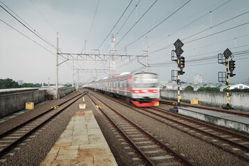 From a train platform's end, a broad view reveals numerous overhead cables, essential for powering...