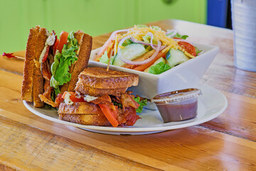 bacon, lettuce, tomato grilled cheese sandwich served with a side salad