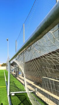 Vista lateral de porter&iacute;a de f&uacute;tbol con detalle de red y campo en alta definici&oacute;n.

