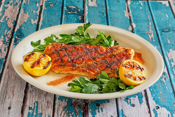Tex-mex rubbed fish fillet grilled and served with grilled lemons and fresh parsley