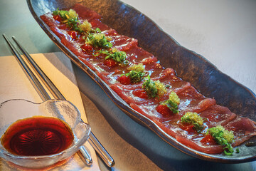 sashimi platter with slices of raw fish topped with seaweed and wasabi