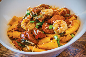 rigatoni pasta dish with sautéed shrimp, sausage, and chicken topped with grated cheese
