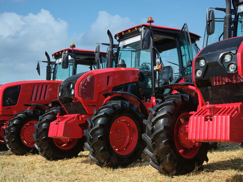 Several large modern red tractors standing in a field.