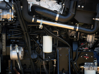 Close up of open hood of agricultural loader with bucket. View of engine and cooling radiator.