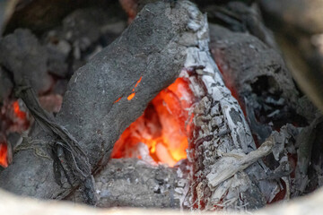 Burnt firewood coal and red hot embers in a clay stove after cooking, Bangladesh village home. Close-up inside rural kitchen.