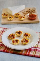 phyllo dough cups stuffed with brie cheese and topped with a sweet and spicy red sauce