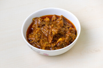 Flavorful Bengali beef bhuna curry in white bowl on wood. A very tasty dish.