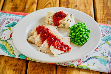 sliced turkey breast, mashed potatoes, and steamed peas with a spicy cranberry gravy