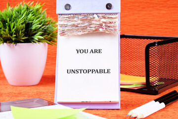 Concept text YOU ARE UNSTOPPABLE written on the calendar page among the stationery