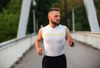 Young athletic man running or jogging on a city bridge, active healthy lifestyle.