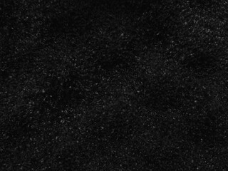 Textured black surface resembling a softly illuminated velvety material with fine details and subtle variations across the texture that create a rich and deep appearance