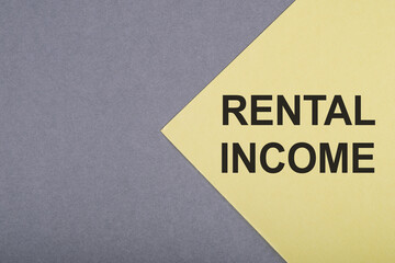 Close Up of Yellow Paper With Black Text Rental Income on Grey Background