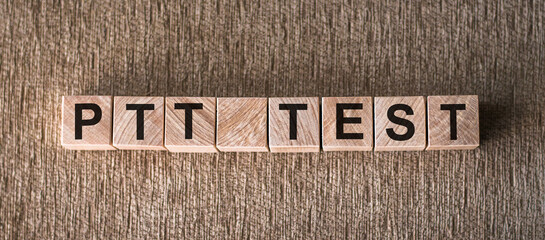 A wooden block arrangement forming the word PTT TEST on a flat surface.