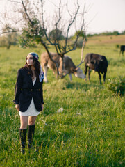 Young woman herding cows on a green pasture in the countryside.