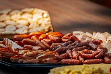 A close-up of a platter filled with various smoked sausages and sliced meats, featuring vibrant red and brown hues and rich textures.