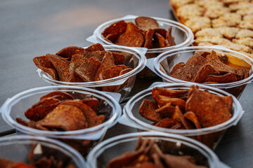 Multiple cups filled with crispy rye bread chips, seasoned with spices and arranged on a wooden table for serving or snacking.