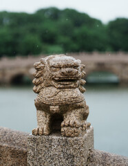 Stone lions on the ancient bridge in the rain