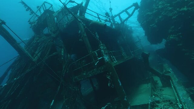The wheelhouse of a sunken trawler rests tilted between steep reef walls in the Red Sea. Underwater wide-angle view. Check my portfolio for more shipwreck footage.