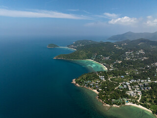 Aerial view of lush coastline, turquoise bays, and distant hills under a bright sky. Ko Pha Ngan, Thailand.