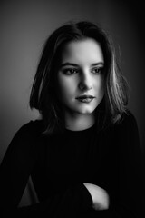 Naklejka premium Black and white portrait of a young beautiful dark-haired girl in a low key.