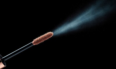 Close up mascara brush with fine mist ejecting on black background