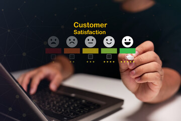 A person interacts with a digital customer satisfaction scale featuring five emoticons from sad to happy, indicating feedback on a laptop.