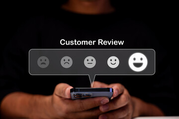 A person holding a smartphone with a customer review rating scale, highlighting the happiest face for positive feedback.