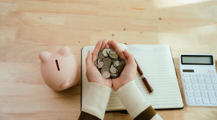 An Asian woman is putting money in a piggy bank while looking at a calculator, giving advice on...