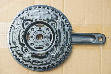 Obraz premium one detail of a sports bicycle made of black iron bicycle sprockets with a knee for a pedal lie on a cut cardboard table