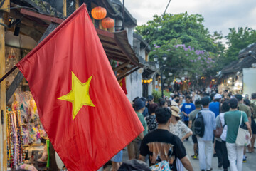 Vietnam national flag flying over bustling street scene at sunset, Vietnam