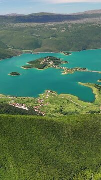 Vertical aerial view of Rama Lake, a beautiful and breathtaking lake with many small islands. It is truly a stunning sight, surrounded by lush green mountain slopes. Bosnia and Herzegovina. 
