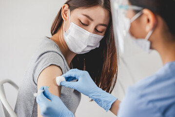 People getting a vaccination to prevent pandemic concept. Woman in medical face mask  receiving a...