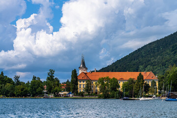 Beautiful view of St. Quirinus parish church on the lake side of Tegernsee lake in summer on a sunny day with blue sky cloud, Tegernsee, Bavaria, Germany