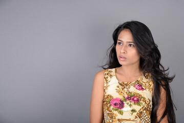A charming young woman wearing a floral patterned top, black leggings and black heels, posing with...