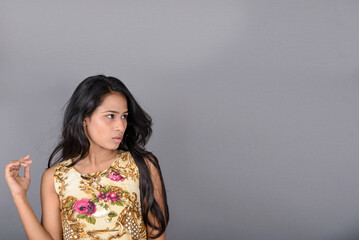 A charming young woman wearing a floral patterned top, black leggings and black heels, posing with...