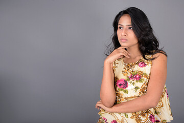 A charming young woman wearing a floral patterned top, black leggings and black heels, posing with...