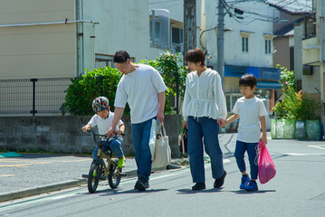 晴天の住宅街を歩く家族4人
