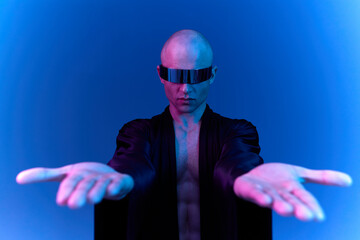 Futuristic man with hands outstretched, showcasing a modern aesthetic. The striking blue light...