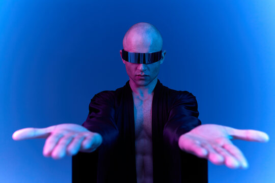 Fototapeta Futuristic man with hands outstretched, showcasing a modern aesthetic. The striking blue light enhances the captivating atmosphere and intriguing look of the image.