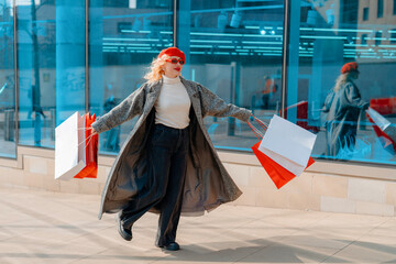 Woman joyfully shopping with colorful bags on a sunny day in an urban setting, showcasing fashion and style in a vibrant environment