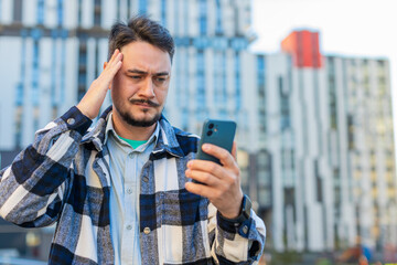 Upset unhappy Caucasian young man guy male using mobile smartphone bad connection losing fortune...