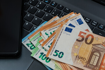 Notebook, Smartphone und Eurogeldscheine